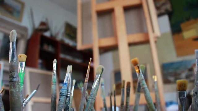 Dirty palette knives and brushes in art studio. The canvas on the easel