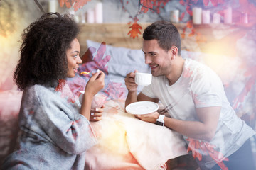 Delicious food. Joyful positive nice people looking at each other and holding bowls with cereal while having a meal together