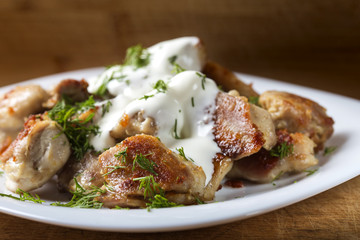 Fried chicken meat with sour cream and dill on plate