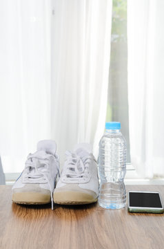 Sport shoes a bottle of water and smart phone on wooden floor, sport lifestyle concept.
