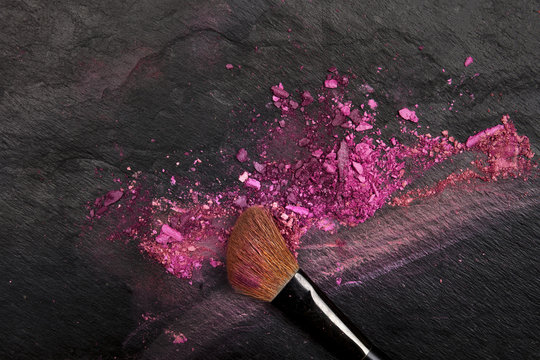 Closeup of makeup brush with eye shadows on black with copy space