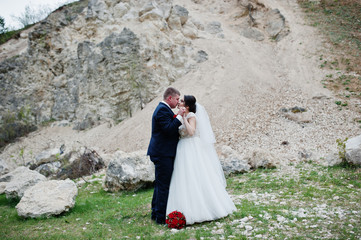 Romantic newly married couple posing and walking in rocky countryside on their wedding day.