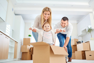 A happy family moves to a new apartment. Mother, father and child with boxes in the room of the new...