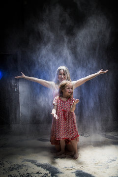 Young mother and small daughter during photoshoot with flour