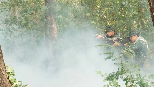 Soldiers team holding gun forward to attack enemy at forest. 