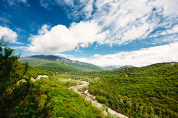Fototapeta na wymiar Scenic mountain landscape with green hills and the river between the mountains, blue sky with clouds. The Caucasus Mountains, Georgia, Europe. Nature and travel background.
