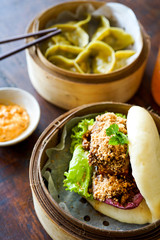 Asparagus tofu dumpling and bao burger with souse. Orange drink. Close-up view