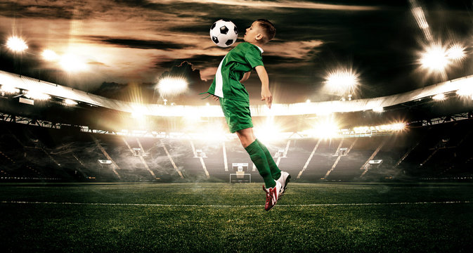 Kid - soccer player. Boy forward in football sportswear on stadium with ball. Sport concept.