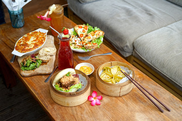 Raclette Tartiflette and salad Chevre Chaud - french kitchen.  Bao burger and Asparagus tofu dumpling - Chinese kitchen. Side view in cafe.