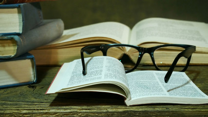 Open Bible with Glasses on the Old Table.