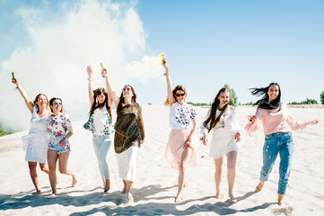Obraz premium Beautiful happy stylish sexy young girls stand beach and hold light up colored smoke bombs. burn up. Sincere smiles. Party in Style boho. Maiden evening Hen-parties. Bachelorette. Close up. Portrait