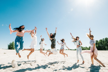 Beautiful stylish happy sexy slim young girls jump on sand beach. Hands decorated buttonhole, Butonierka with ribbons flowers. Party in Style boho. Maiden evening Hen-parties. Bachelorette. Close up