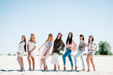 Obraz premium Beautiful stylish happy sexy slim young girls standding sand beach. Hands decorated buttonhole, Butonierka with ribbons flowers. Party in Style boho. Maiden evening Hen-parties. Bachelorette. Close up