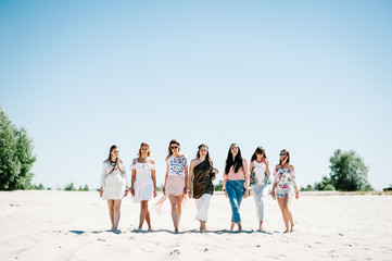 Beautiful stylish happy sexy slim young girls is go sand beach. Hands decorated buttonhole, Butonierka with ribbons flowers. Party in Style boho. Maiden evening Hen-parties. Bachelorette. Close up