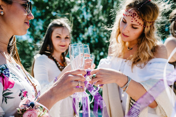 Beautiful sexy Bride's girlfriends ornaments champagne glass, botanier of flowers, ribbons. Buttonholes. Party in Style boho. Maiden evening Hen-parties. Bachelorette. Close up. Background beach sand