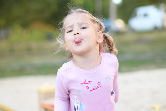 Funny cute little girl shows the tongue