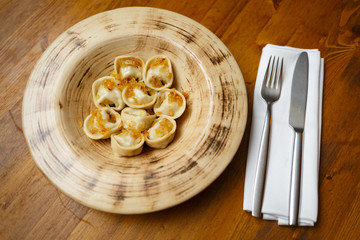 Dumplings sprinkled with fried onions on a plate. Wooden background.
