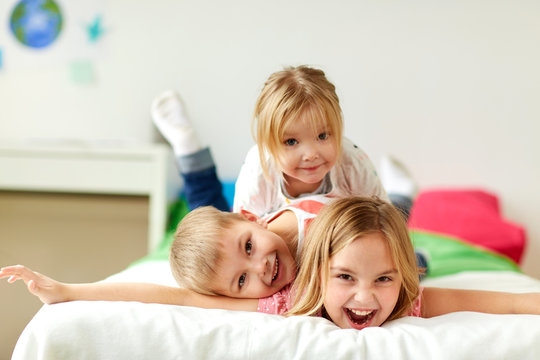happy little kids having fun in bed at home