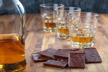 chocolate and three glasses of whiskey on the oak surface of the table