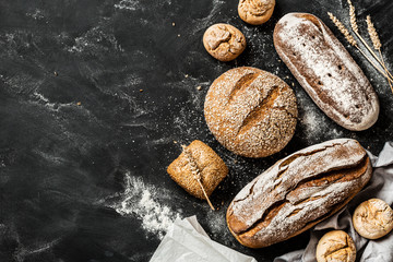 Fototapety  Bakery - rustic crusty loaves of bread and buns on black