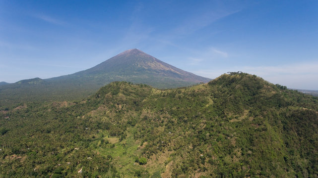 Aerial view of Volcano Mount Agung with smoke billowing out at sunrise, Bali, Indonesia. Conical volcano of Gunung Agung. Rural mountain landscape.
