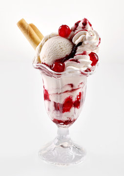 Sundae topped with fruit sauce in glass cup