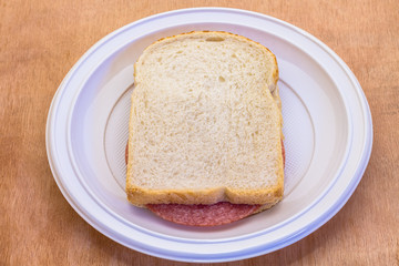 sandwich white bread with slice of sausage meat on white plate