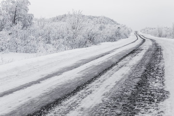 scenic view of empty road with snow covered landscape on cloudy winter day