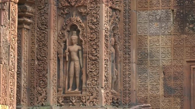zoom in on a stone bas relief carving of a figure at banteay srei in angkor, cambodia