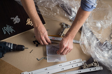 Hands of a man with a tool. Screwdriver, Screws, Furniture Details. Concept Workshop. Flat lay, top view