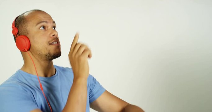 4K Happy confident man with headphones doing funny dance on white background in studio shot. Slow motion.