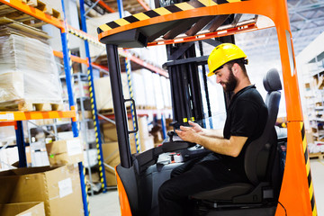 Warehouse worker doing logistics work with forklift loader