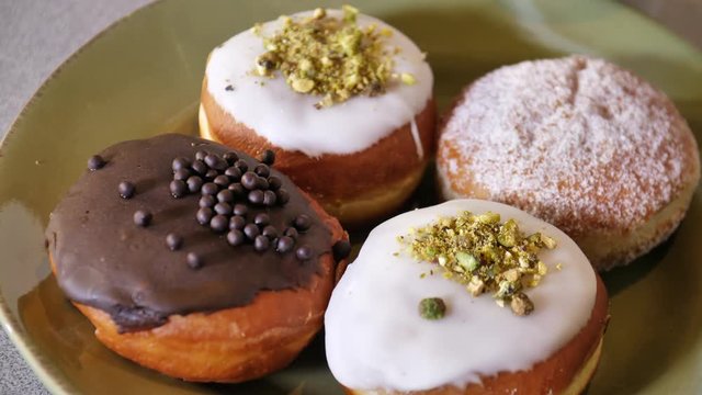 Four Paczki Polish Pastries Frosted Vanilla Chocolate Pistachio Sugar Toppings Fried High Calorie Dessert Sweet Food on Plate