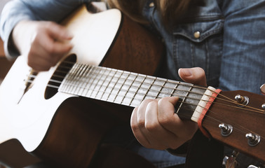 Fototapeta premium Young girl playing acoustic guitar with jeans shirt