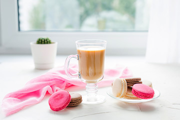 Coffee with milk and some sweet french coockies on the white table. Breakfast time. 