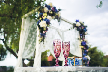 Beautiful wedding arch and table with glasses in nature. Wedding decorations.