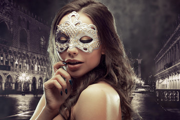 Obraz na płótnie Canvas Beautiful brunette with Venetian mask. Young and beautiful woman on Venetian view background.