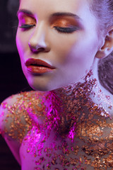 Beautiful girl with creative image with gold foil on the neck. Blue and purple toning