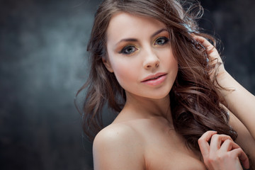 Fototapeta premium Brunette girl with long wavy hair . Beautiful model with curly hairstyle