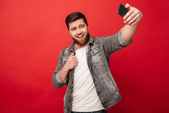 Image of Pleased bearded man making selfie on smartpphone