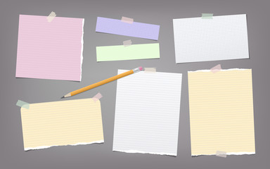 Torn colorful and white note, notebook paper strips, sheets, pencil for text stuck with adhesive tape on dark gray background. © flas100