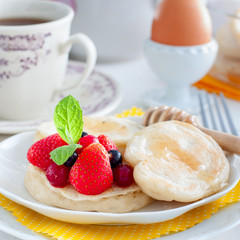 Homemade breakfast with pancakes, berries, honey and tea, square