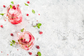 Cold summer drink, Raspberry Sangria, Lemonade or Mojito with fresh Raspberry and syrup, mint leaves, on grey stone background copy space top view