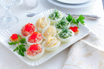 Festive serving of stuffed eggs with filling options - red, yellow, green. Selective focus, horizontal