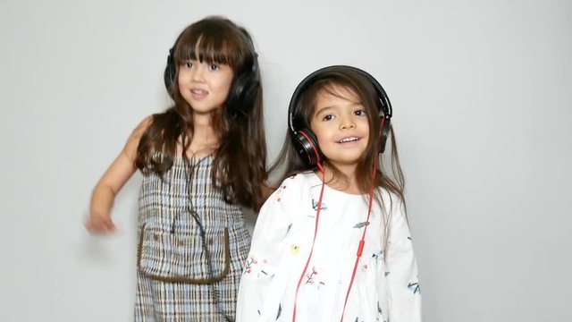 two adorable sister mixed race girl enjoy with music and dancing with headphones. leisure activities to strengthen family ties on holiday. 