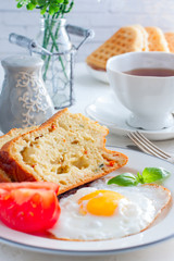 Fresh breakfast with scrambled eggs, fresh tomatoes and sliced pieces of muffins with mozzarella and sun-dried tomatoes, selective focus