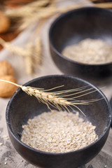 Useful breakfast. Still life with dry flakes of oatmeal in black exquisite bowls on textiles.