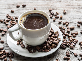 Cup of coffee surrounded by coffee beans. Top view.