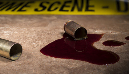 Crime scene tape behind empty brass and blood