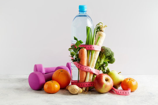 Bottle of water with a pink measuring tape, vegetables and fruit
